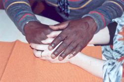 Les mains blanches de Gabriela sont posées délicatement dans les mains noires de son ami africain.